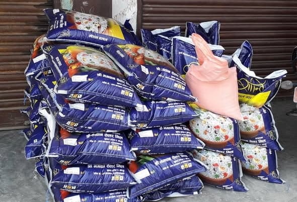 Sacks of rice and flour stacked several rows deep in front of a shuttered shopfront.