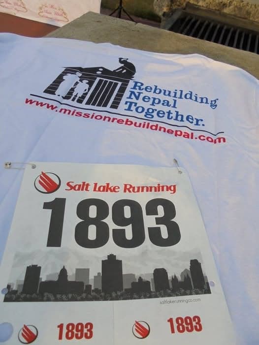 A race number pinned to a white T-shirt printed with the slogan Rebuilding Nepal Together and the organisation's web address