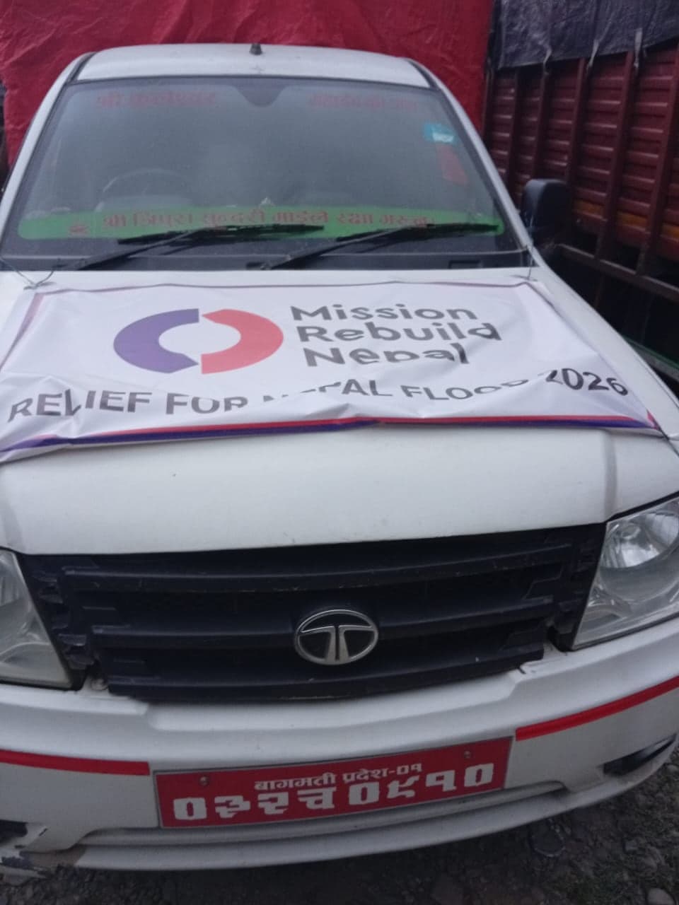 A banner taped across the bonnet of a white pickup truck reading Mission Rebuild Nepal, Relief for Nepal Flood 2026.